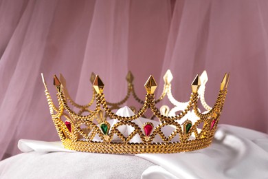 Beautiful golden crown with gems on white cloth