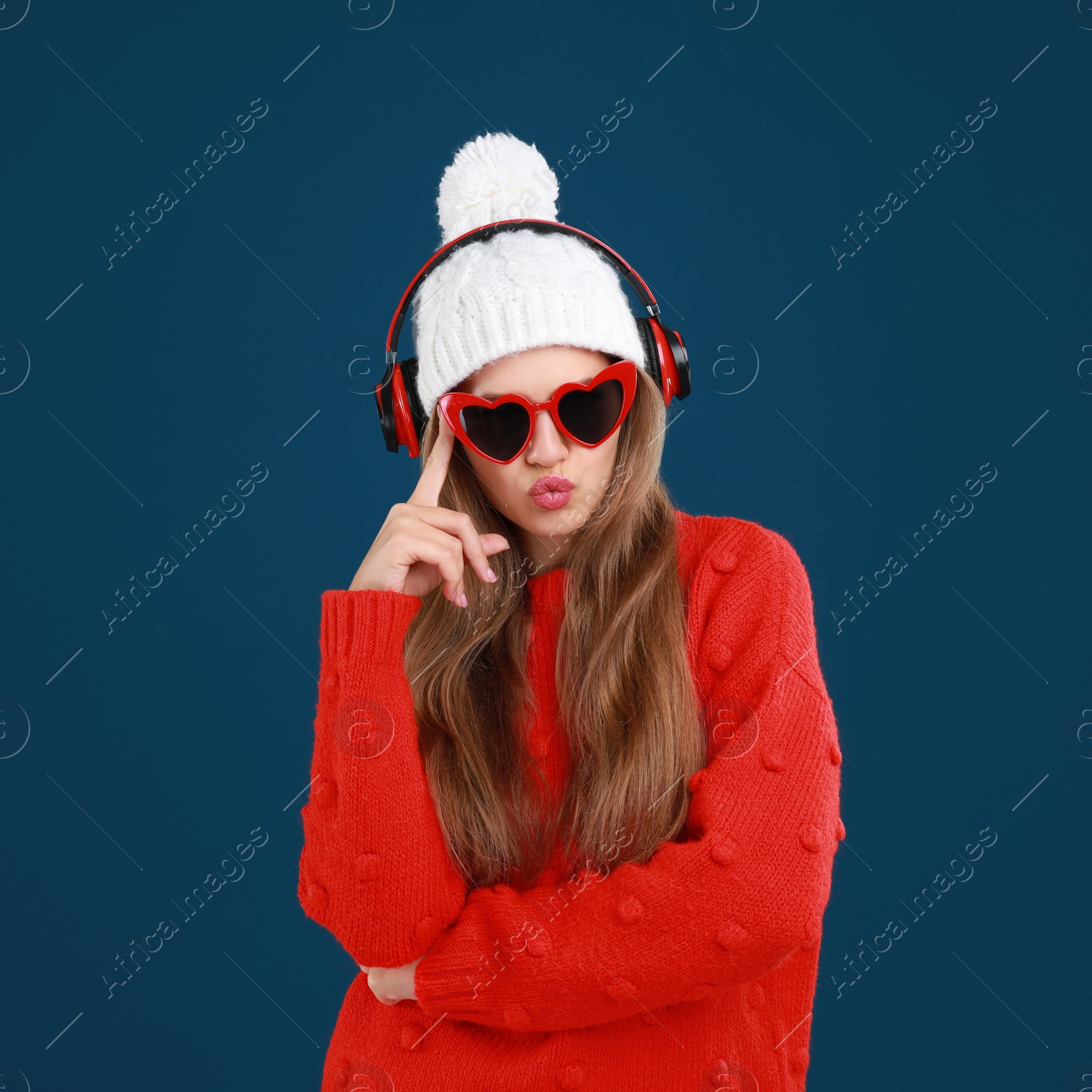 Photo of Young woman listening to music with headphones on dark blue background