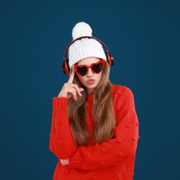 Young woman listening to music with headphones on dark blue background