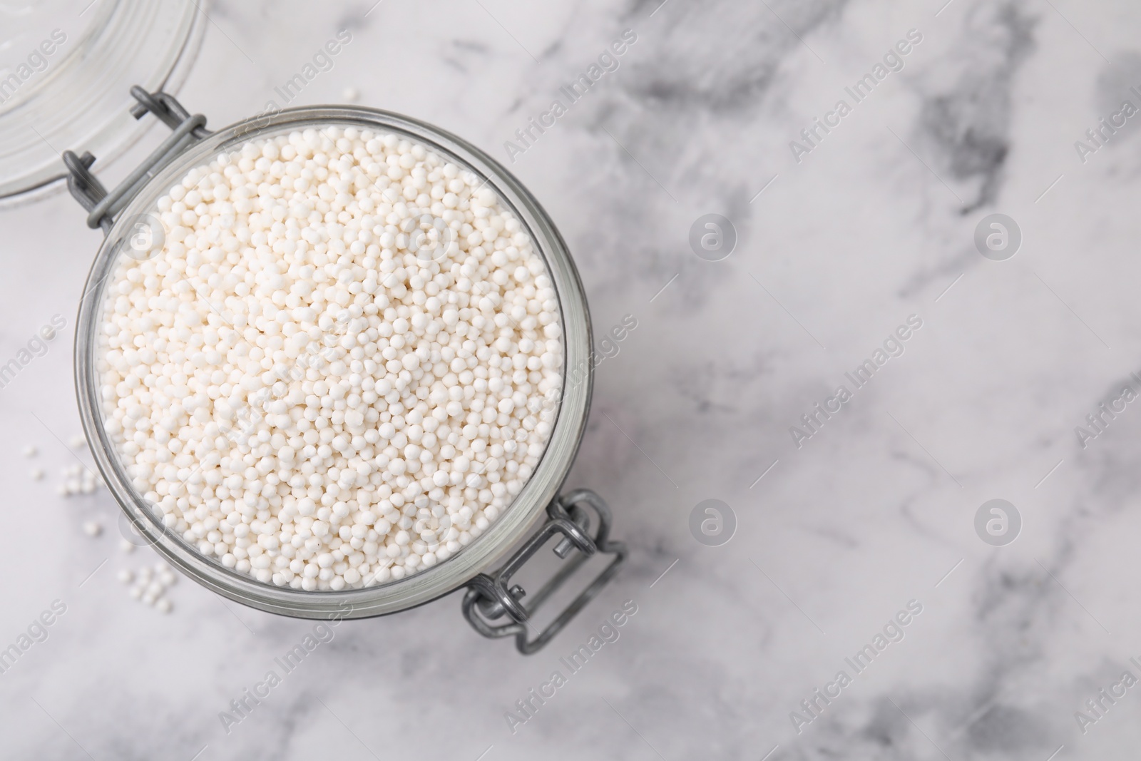 Photo of Tapioca pearls in jar on white marble table, top view. Space for text
