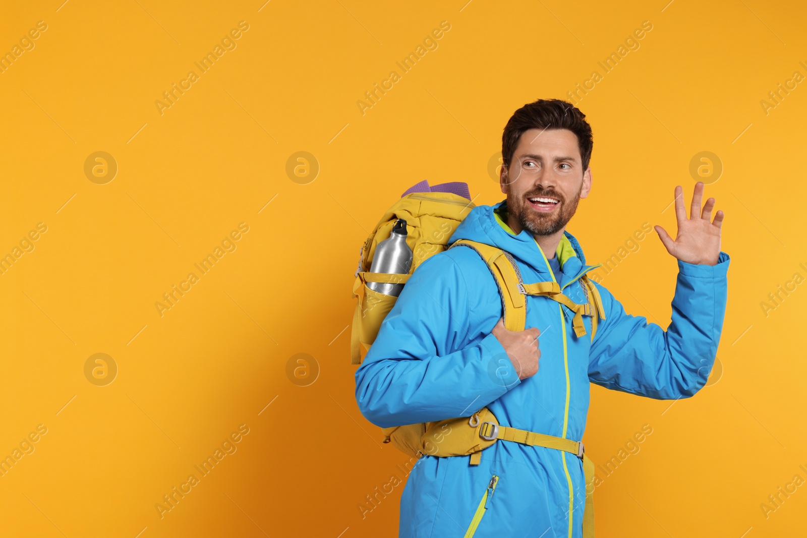 Photo of Happy man with backpack on orange background, space for text. Active tourism