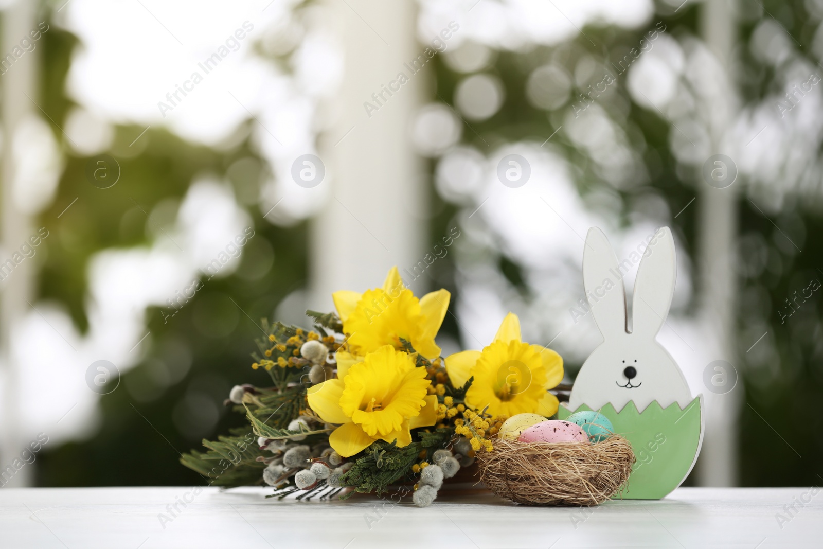 Photo of Festive composition with Easter eggs in decorative nest on table against blurred window