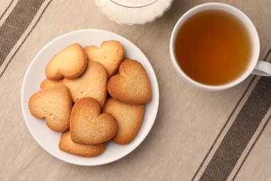 Photo of Heart shaped Danish butter cookies and tea on table, flat lay