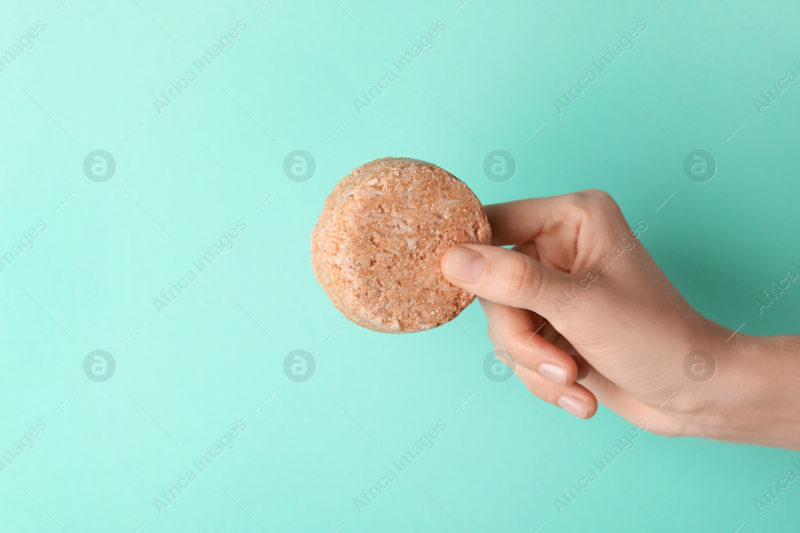 Photo of Woman holding solid shampoo bar against turquoise background, closeup. Space for text