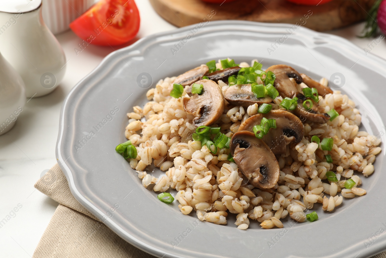 Photo of Delicious pearl barley with onion and mushrooms on white table, closeup