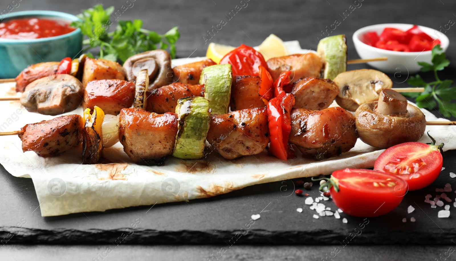 Photo of Delicious shish kebabs with mushroom, onion, tomato and zucchini on grey table, closeup