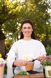 Photo of Woman planting flower into pot in garden