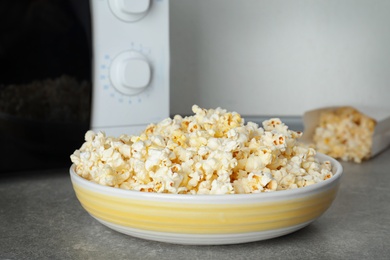 Photo of Bowl with tasty popcorn on table in kitchen