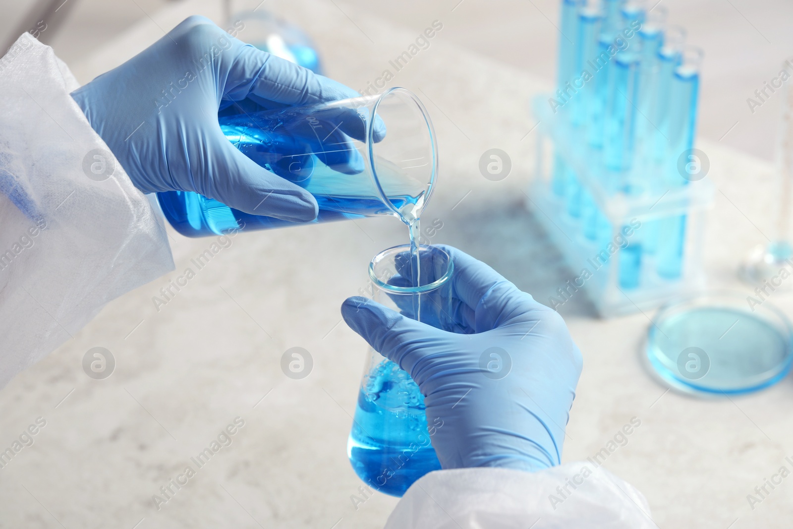 Photo of Scientist working with beakers at grey table, closeup