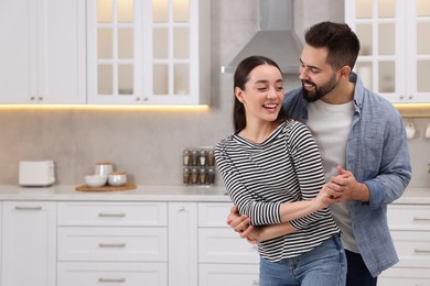 Photo of Happy lovely couple dancing together in kitchen. Space for text