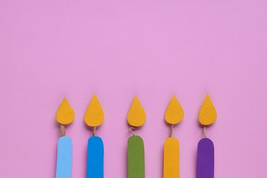 Different paper candles on pink background, flat lay. Space for text