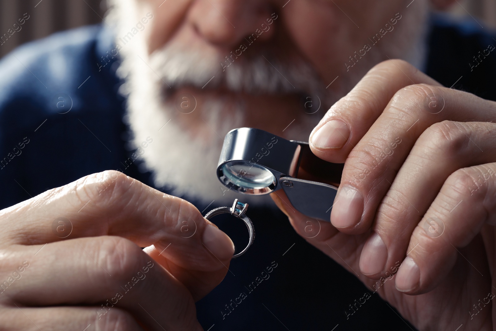 Photo of Professional jeweler working with ring on dark background, closeup