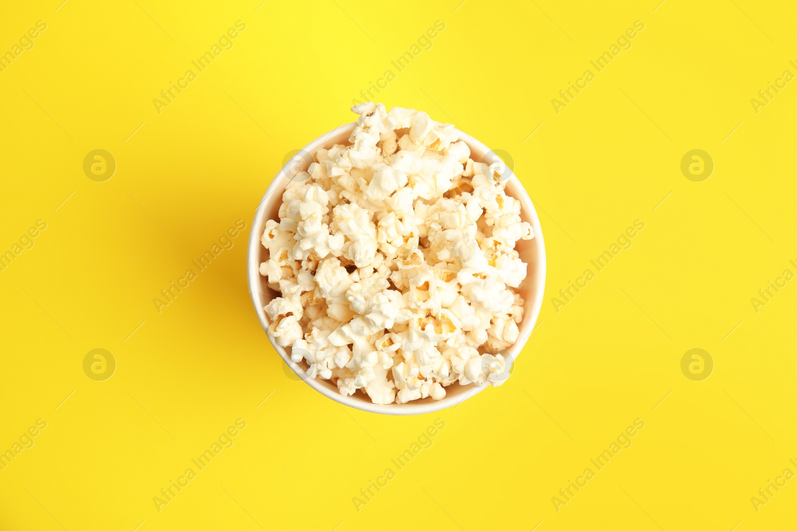 Photo of Tasty pop corn on yellow background, top view