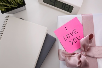 Photo of Memory sticker with phrase I Love You on gift box at table, flat lay. Valentine's Day celebration