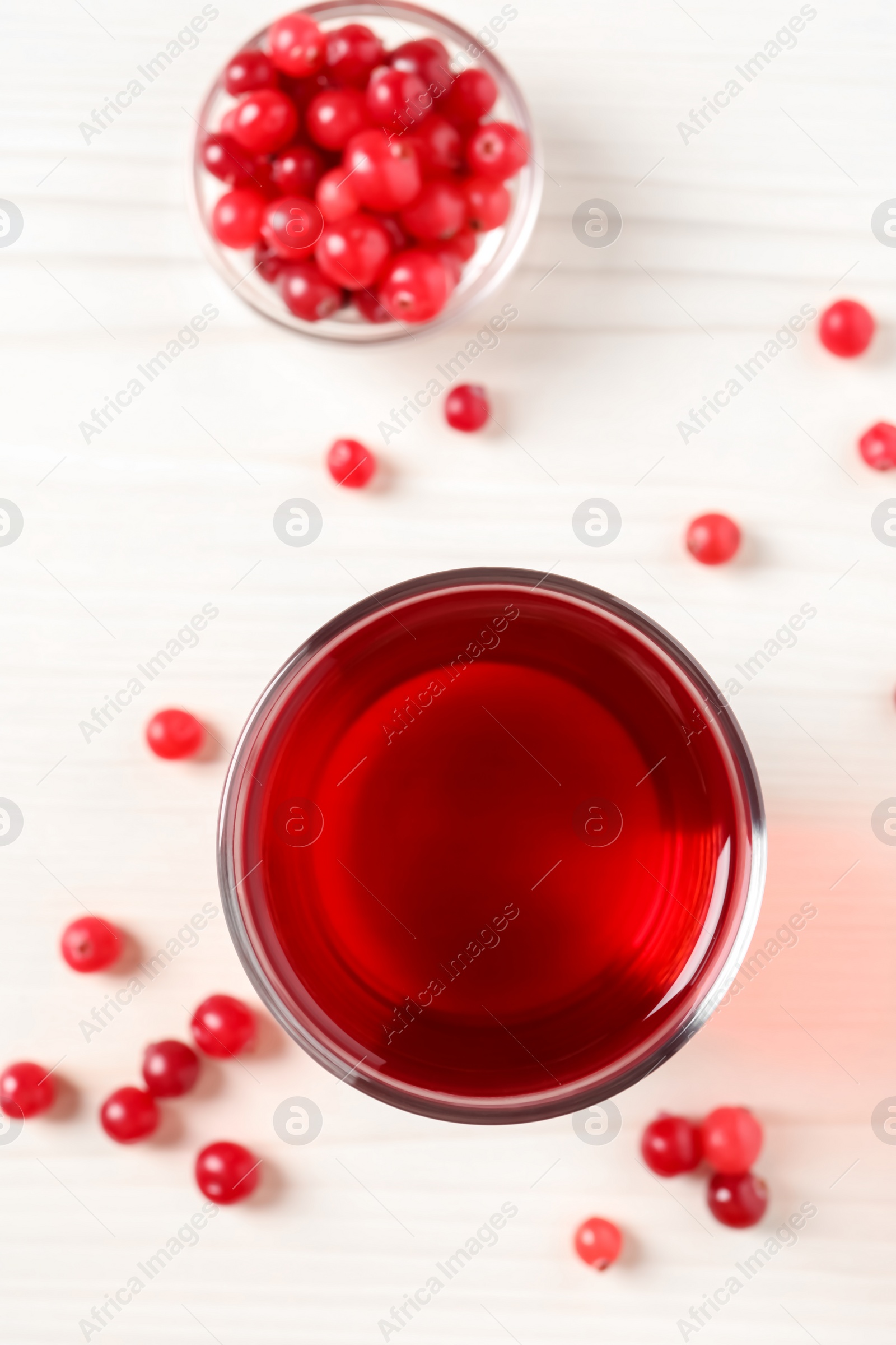 Photo of Tasty cranberry juice in glass and fresh berries on white wooden table, flat lay