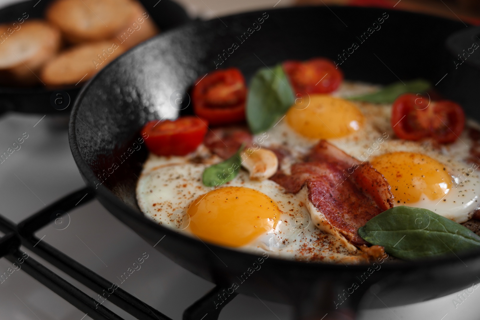 Photo of Delicious fried eggs with bacon and tomatoes in pan, closeup