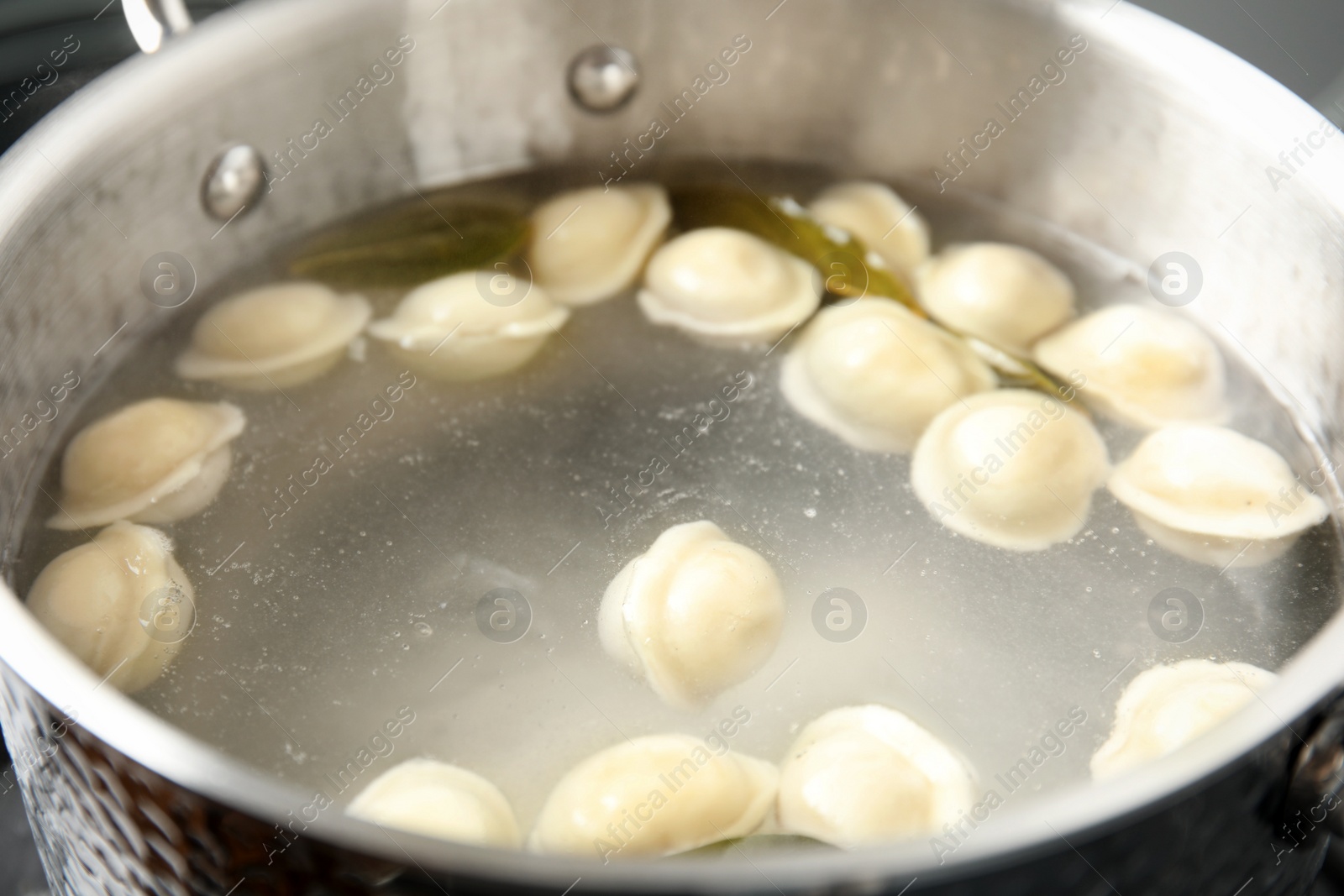 Photo of Closeup of metal stewpan with boiling water and dumplings. Home cooking