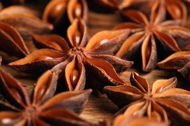 Photo of Aromatic anise stars on wooden table, closeup