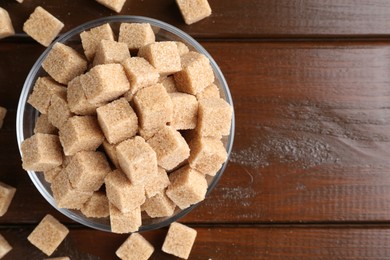 Photo of Brown sugar cubes on wooden table, flat lay. Space for text