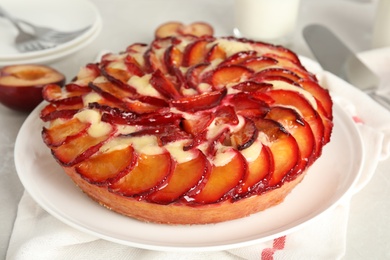 Delicious cake with plums on light table, closeup