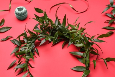 Unfinished mistletoe wreath and florist supplies on red background. Traditional Christmas decor