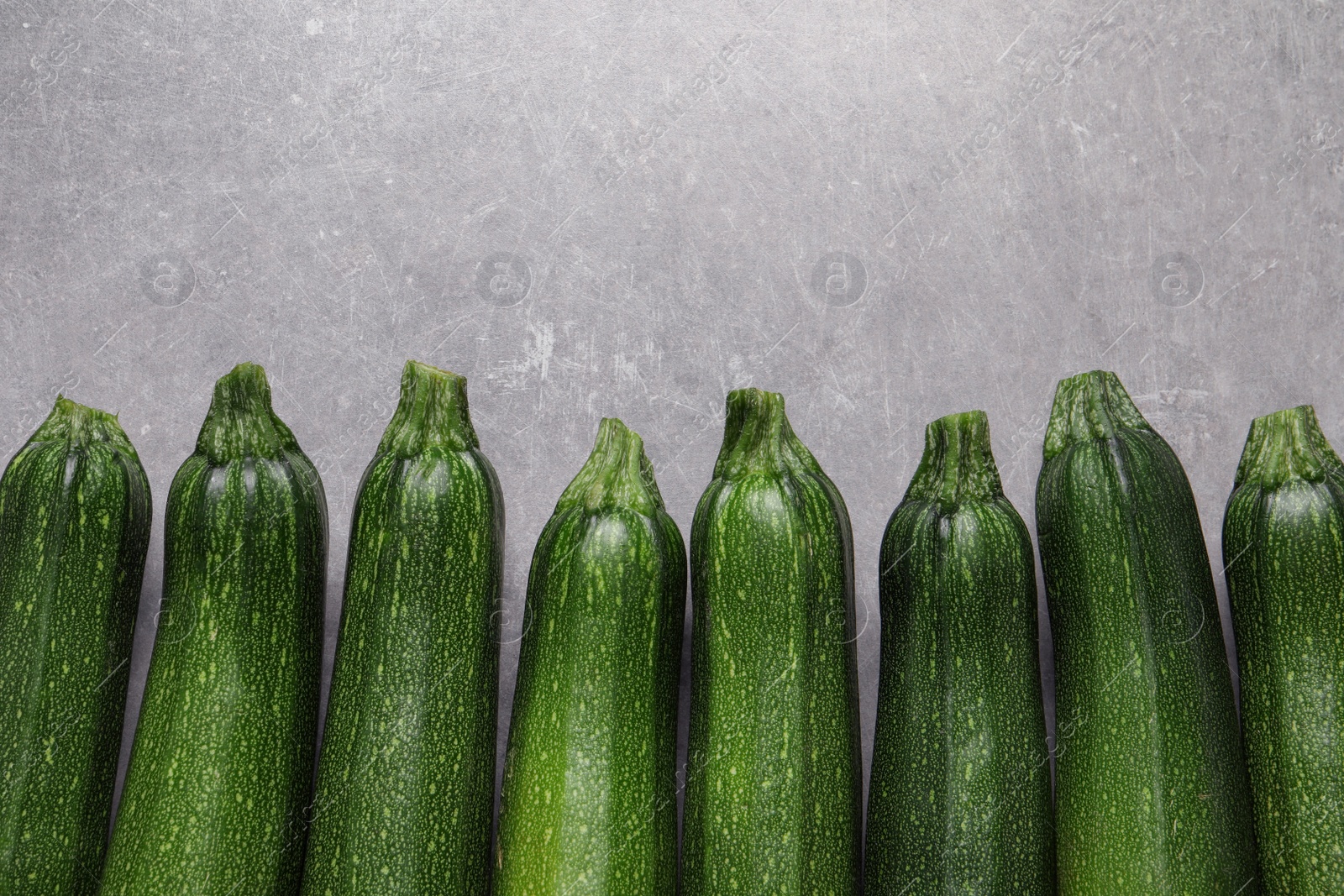 Photo of Raw ripe zucchinis on light grey table, flat lay. Space for text