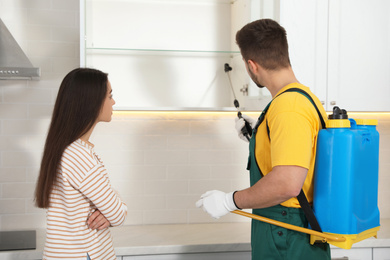Woman showing insect traces to pest control worker in kitchen