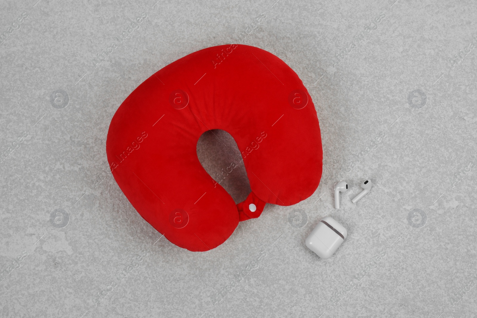 Photo of Soft travel pillow and earphones on grey textured background, top view