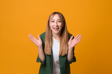 Photo of Beautiful young woman laughing on yellow background. Funny joke
