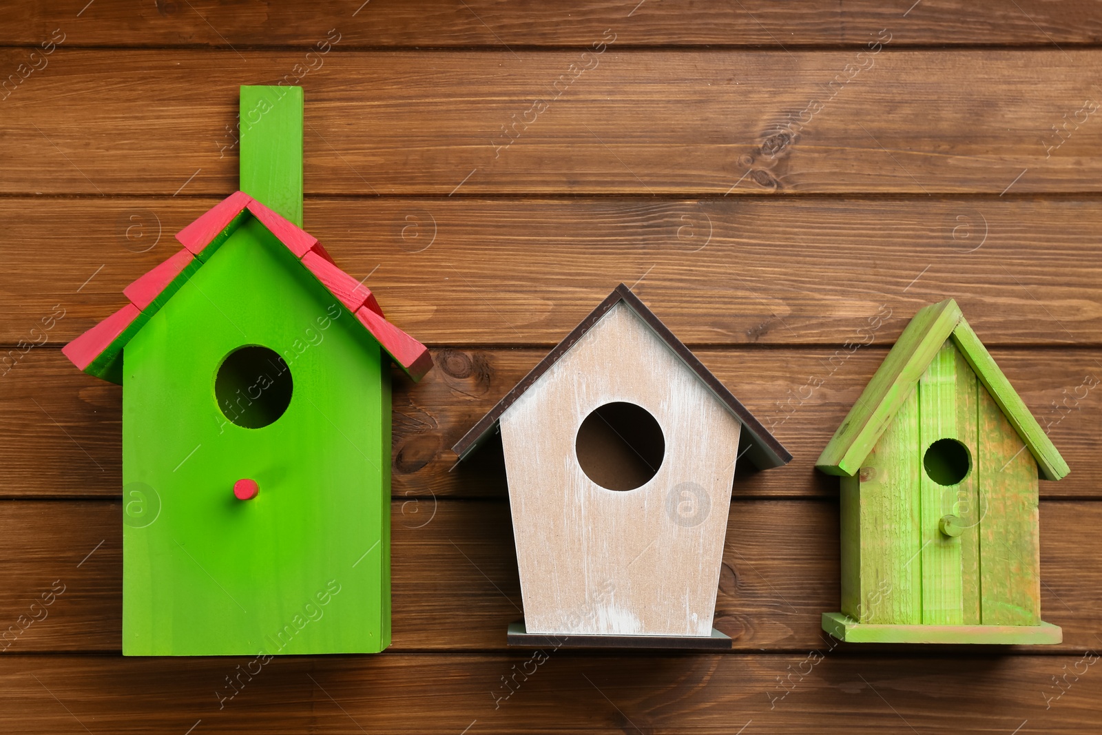 Photo of Three different bird houses on wooden background