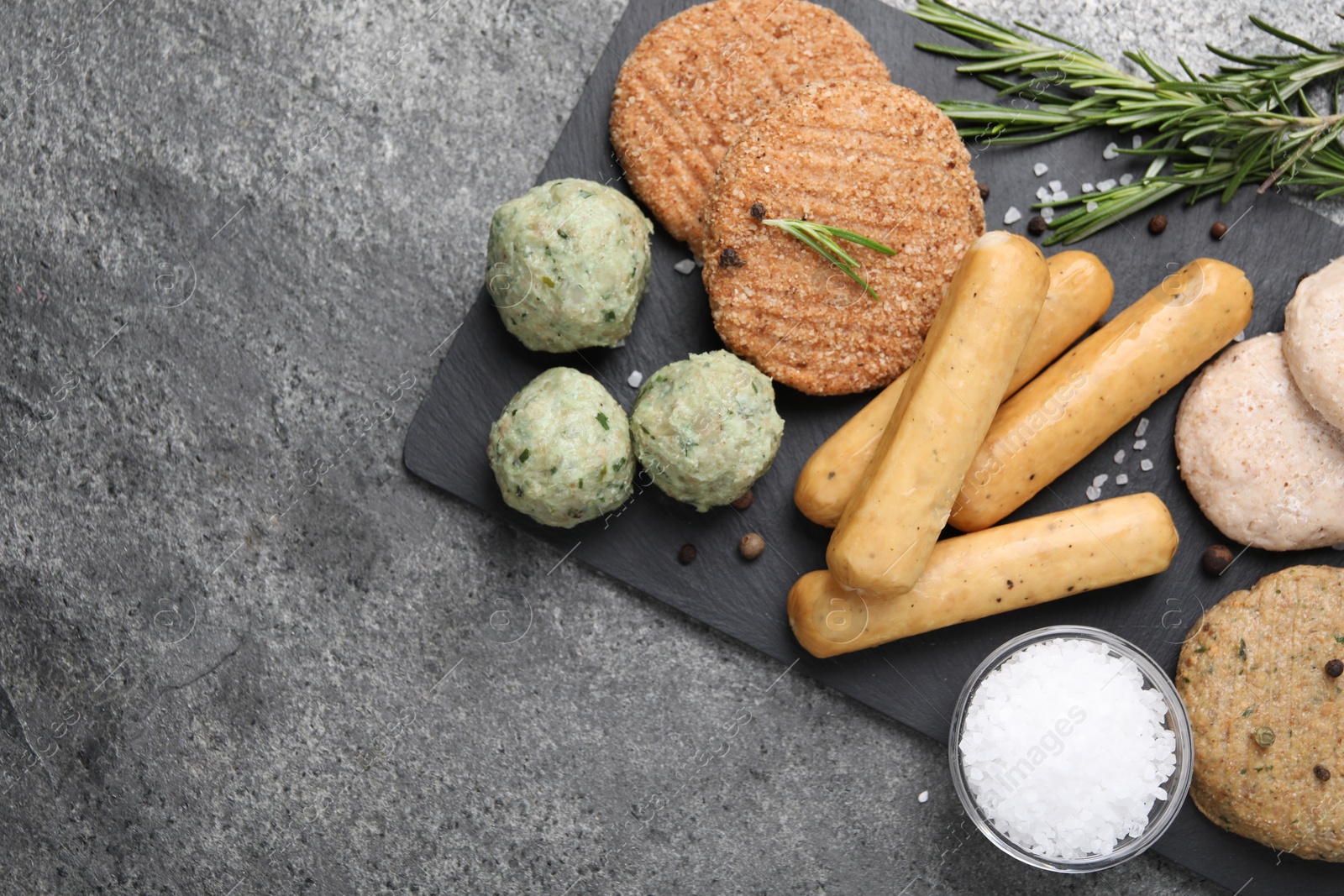 Photo of Different raw vegan meat products, salt and rosemary on grey table, flat lay. Space for text