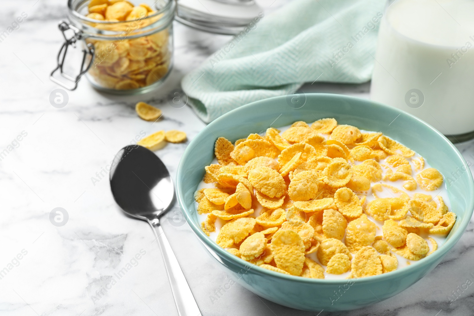 Photo of Tasty crispy corn flakes with milk on marble table