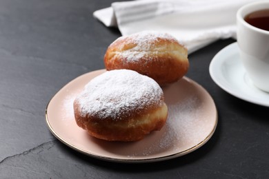 Delicious sweet buns and cup of drink on dark gray table, closeup