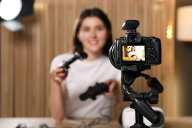 Photo of Technology blogger explaining something while recording video at home, focus on camera