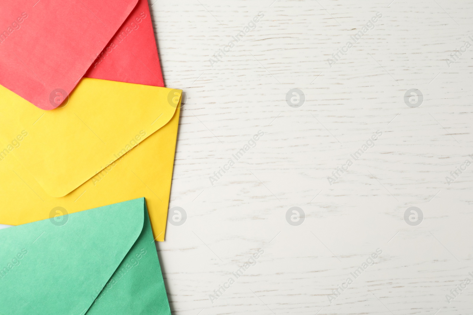 Photo of Colorful paper envelopes on white wooden background, flat lay. Space for text