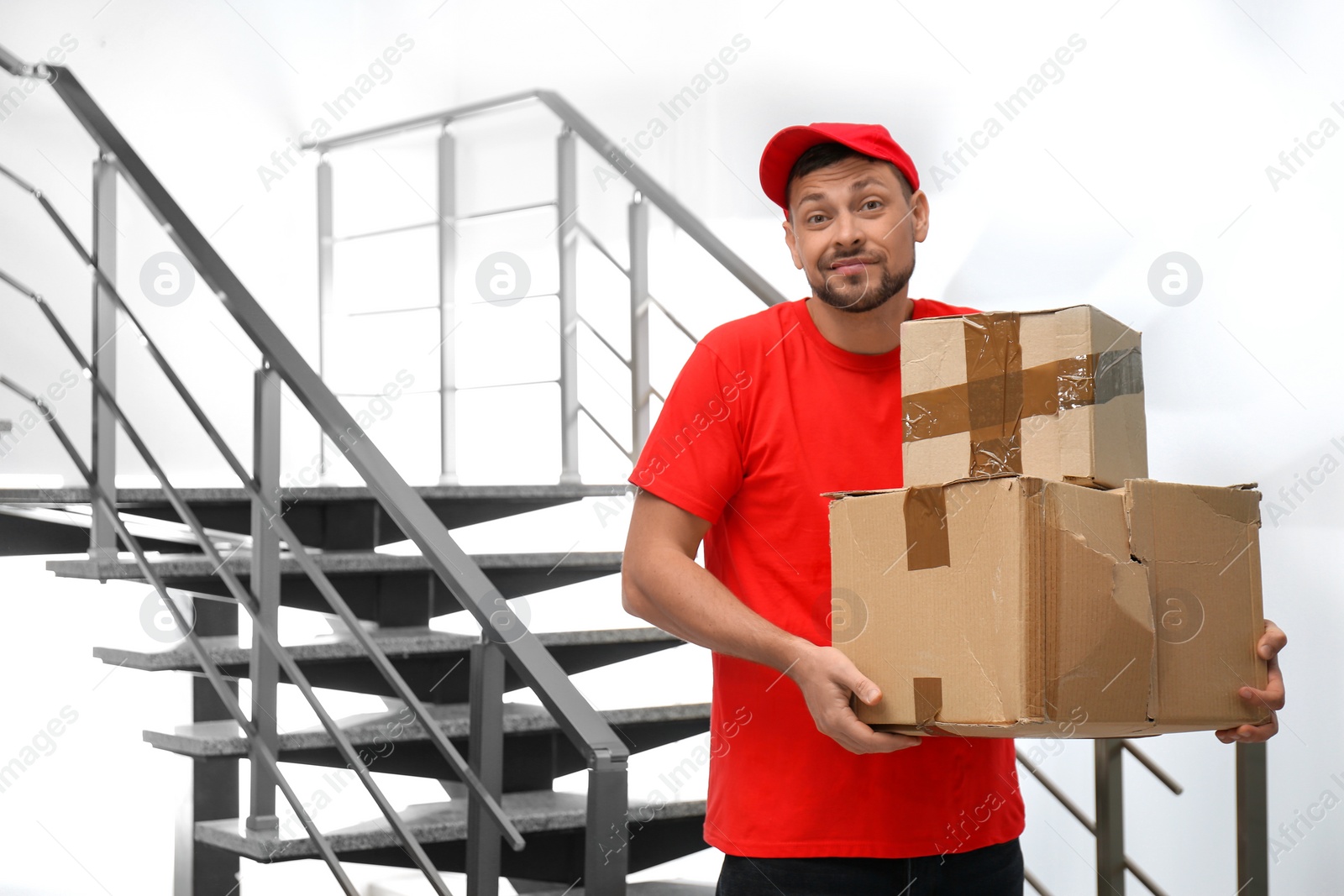 Photo of Emotional courier with damaged cardboard boxes indoors. Poor quality delivery service