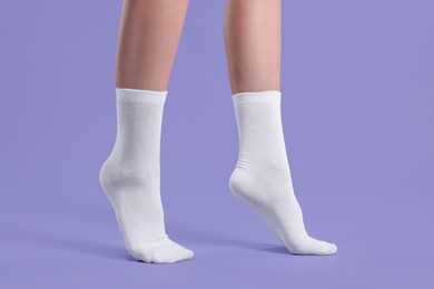 Woman in stylish white socks on violet background, closeup