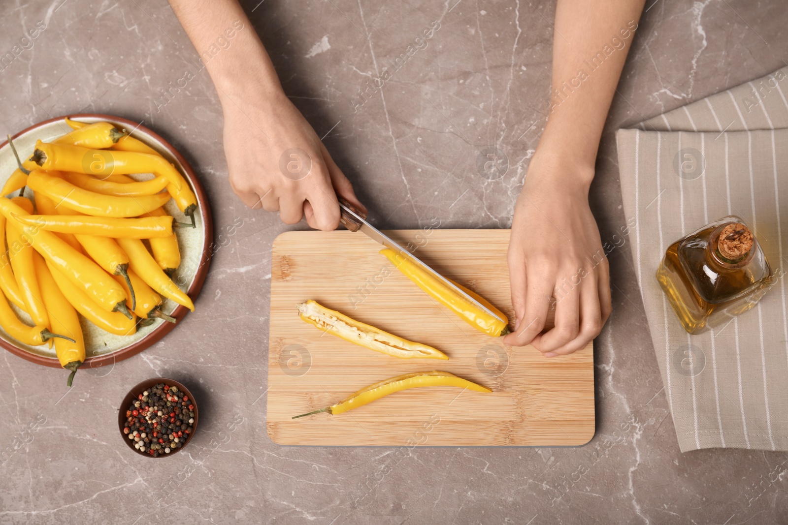 Photo of Woman cutting chili peppers at table, top view