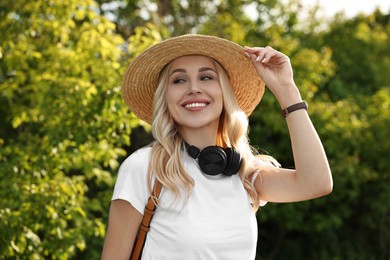 Happy young woman with headphones in park on spring day