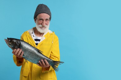 Fisherman with caught fish on light blue background, space for text