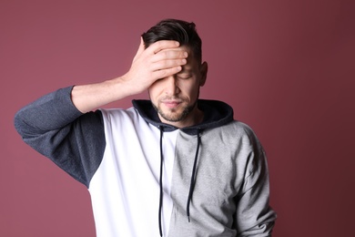Man suffering from headache on color background