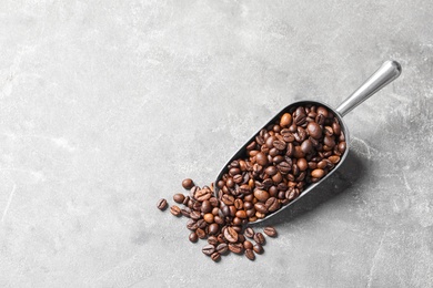 Photo of Scoop with roasted coffee beans on grey background, top view. Space for text