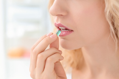 Photo of Young woman taking pill indoors