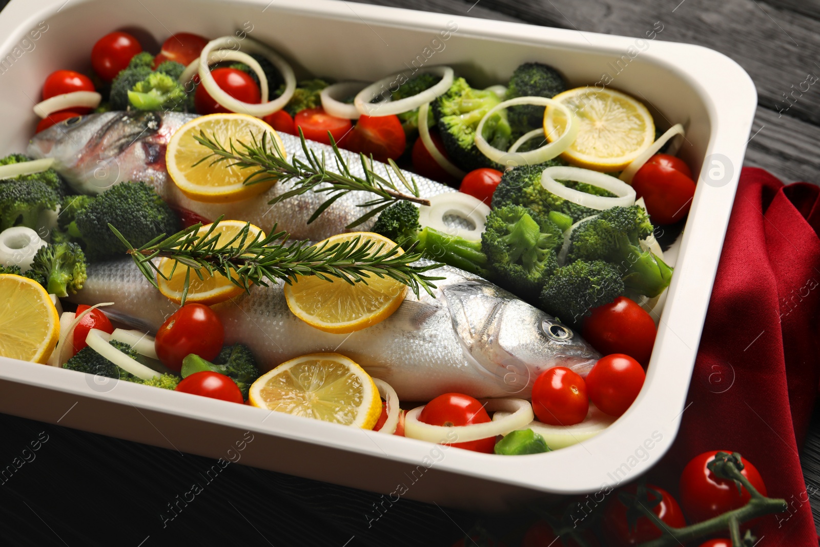 Photo of Raw fish with vegetables and lemon in baking dish on table