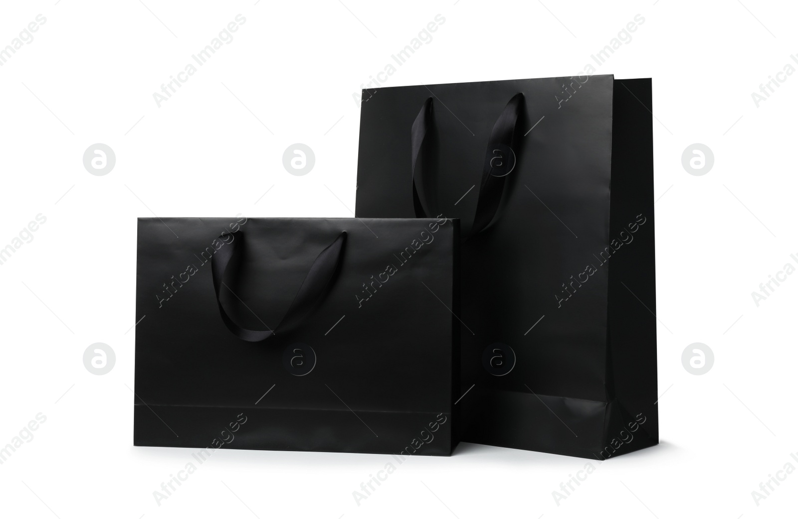 Photo of Paper shopping bags with ribbon handles on white background. Mockup for design