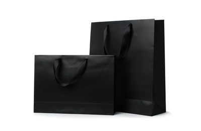 Paper shopping bags with ribbon handles on white background. Mockup for design