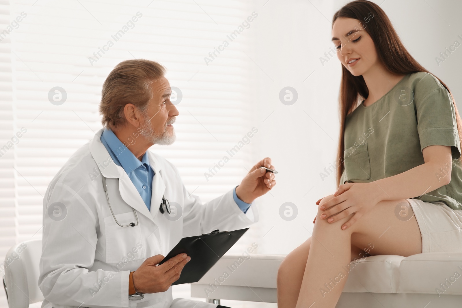 Photo of Orthopedist examining patient with injured knee in clinic