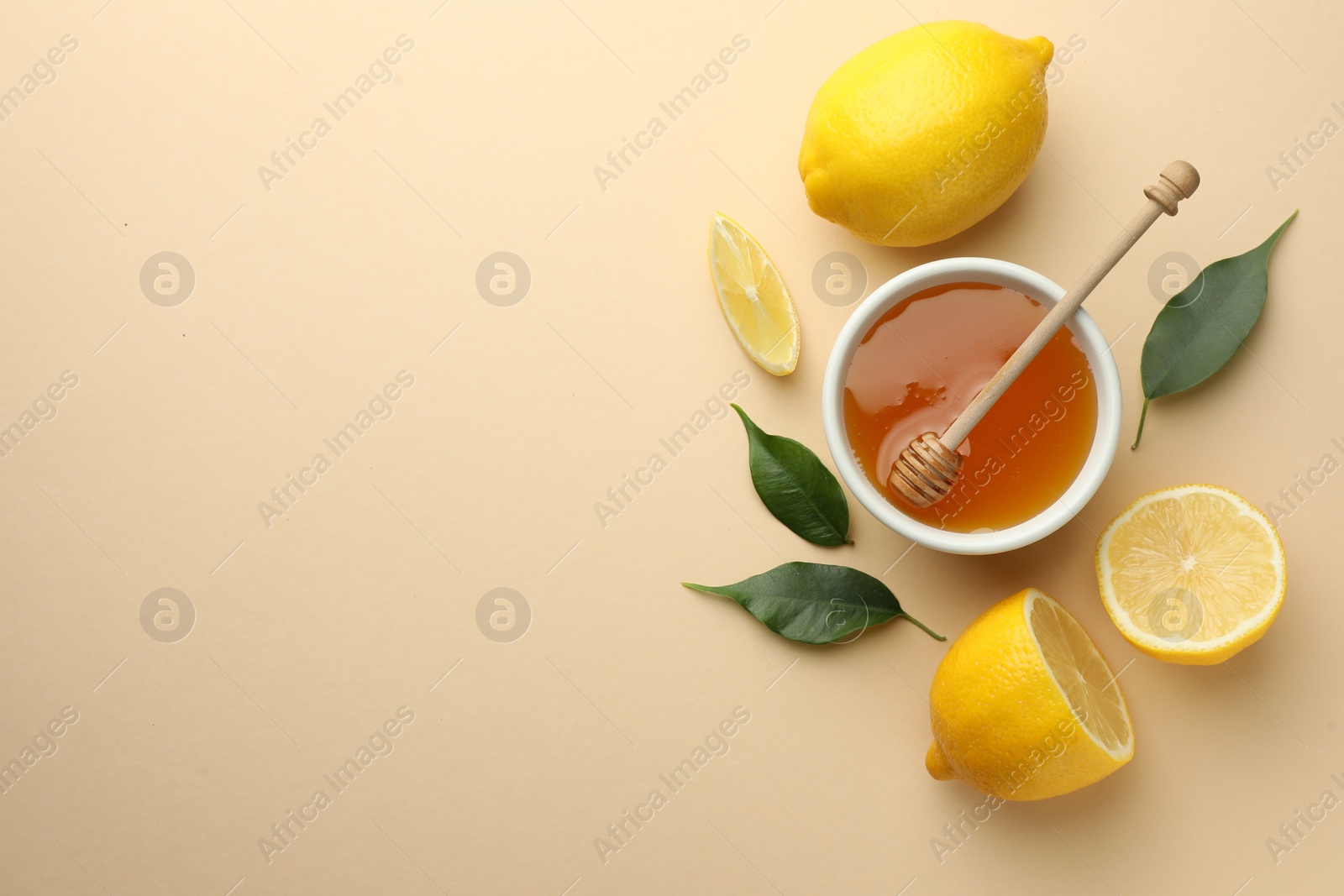 Photo of Ripe lemons, leaves, bowl of honey and dipper on beige background, flat lay. Space for text