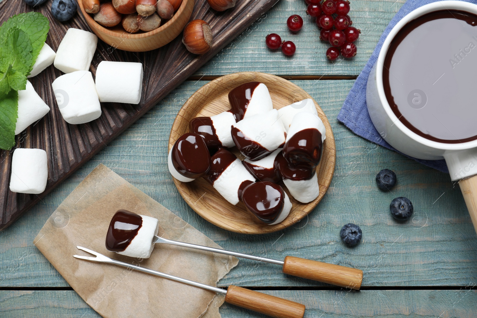 Photo of Delicious marshmallows covered with chocolate on wooden table, flat lay