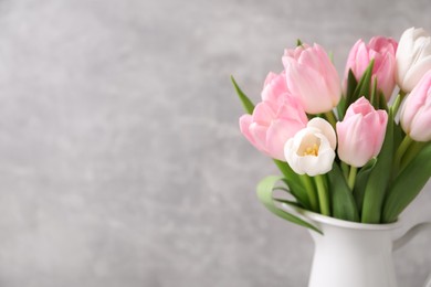 Photo of Beautiful bouquet of tulips in jug against grey background. Space for text